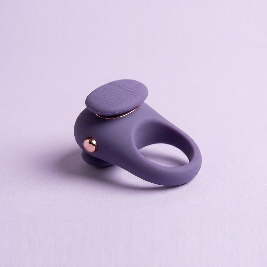 DOVIAR TOUCHE finger vibrator with a wave-textured pad and rose-gold button, on a lilac background
