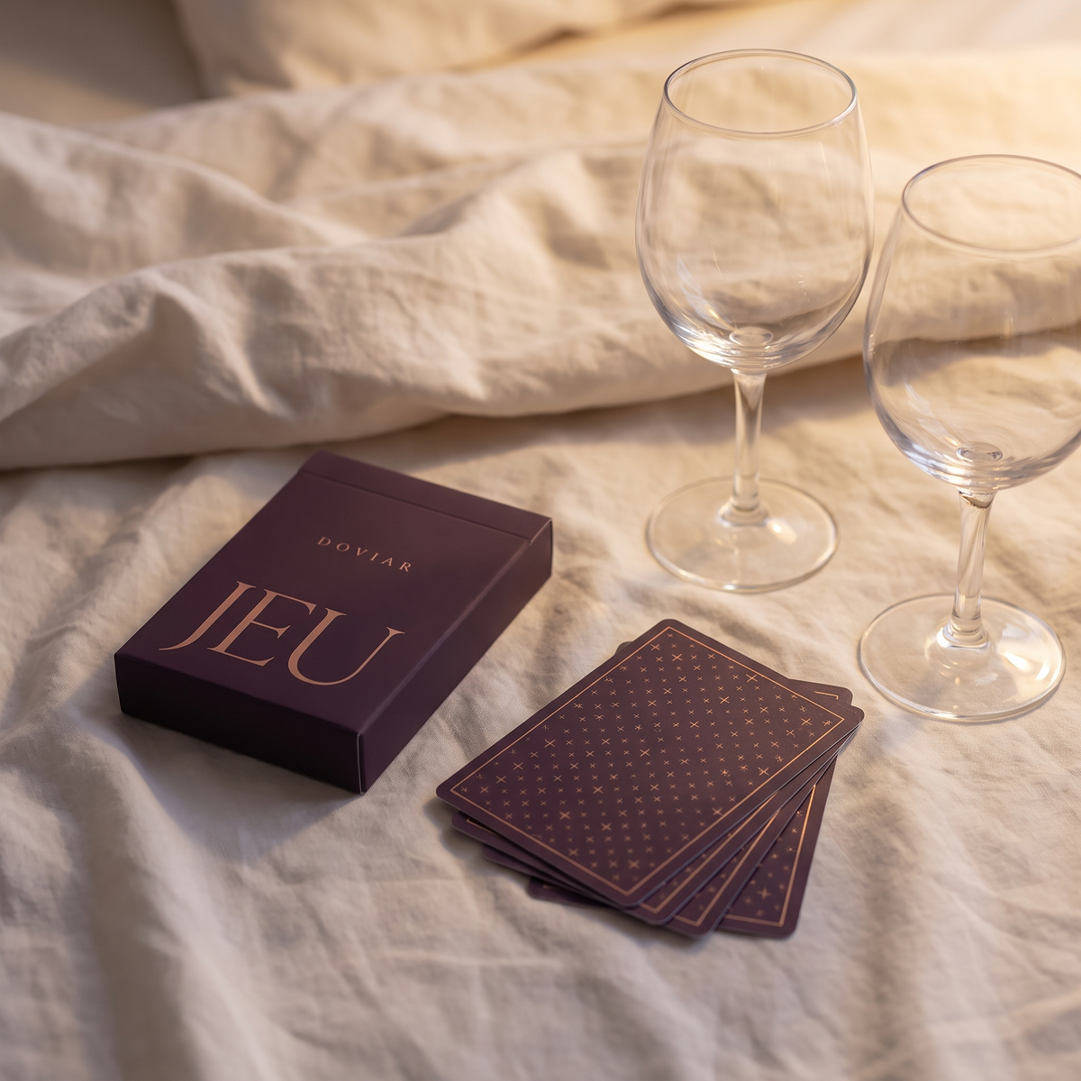 DOVIAR JEU card game for couples on linen bedsheets with two wine glasses